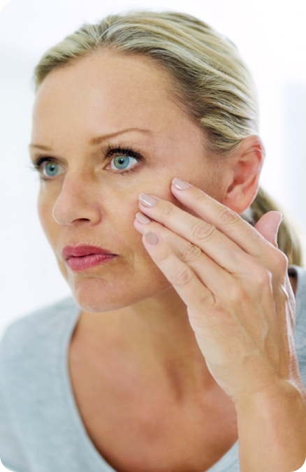Woman touching her cheek and looking in the mirror