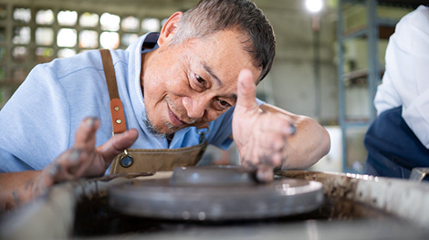 An artist molding on a clay wheel.