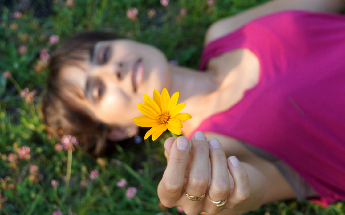 Woman with yellow flower lying on the grass