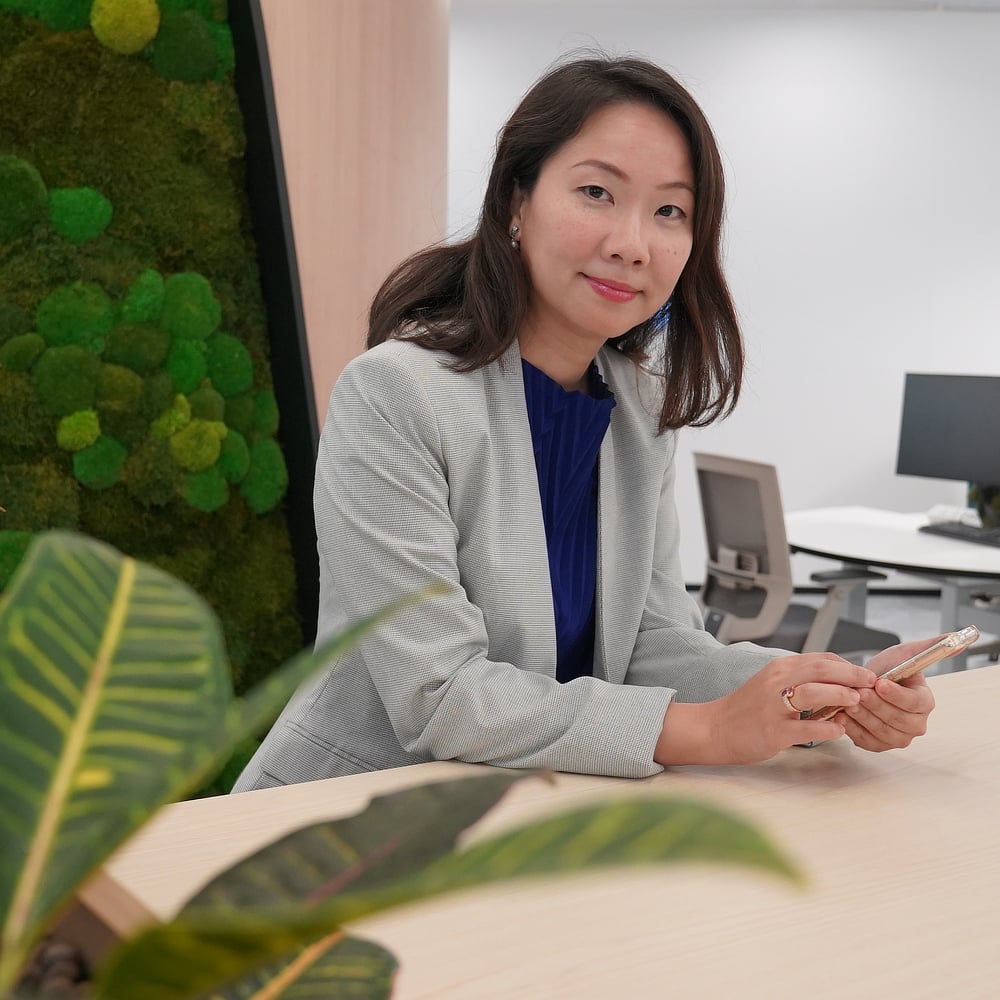 Businesswoman looking at the camera while operating a smartphone.