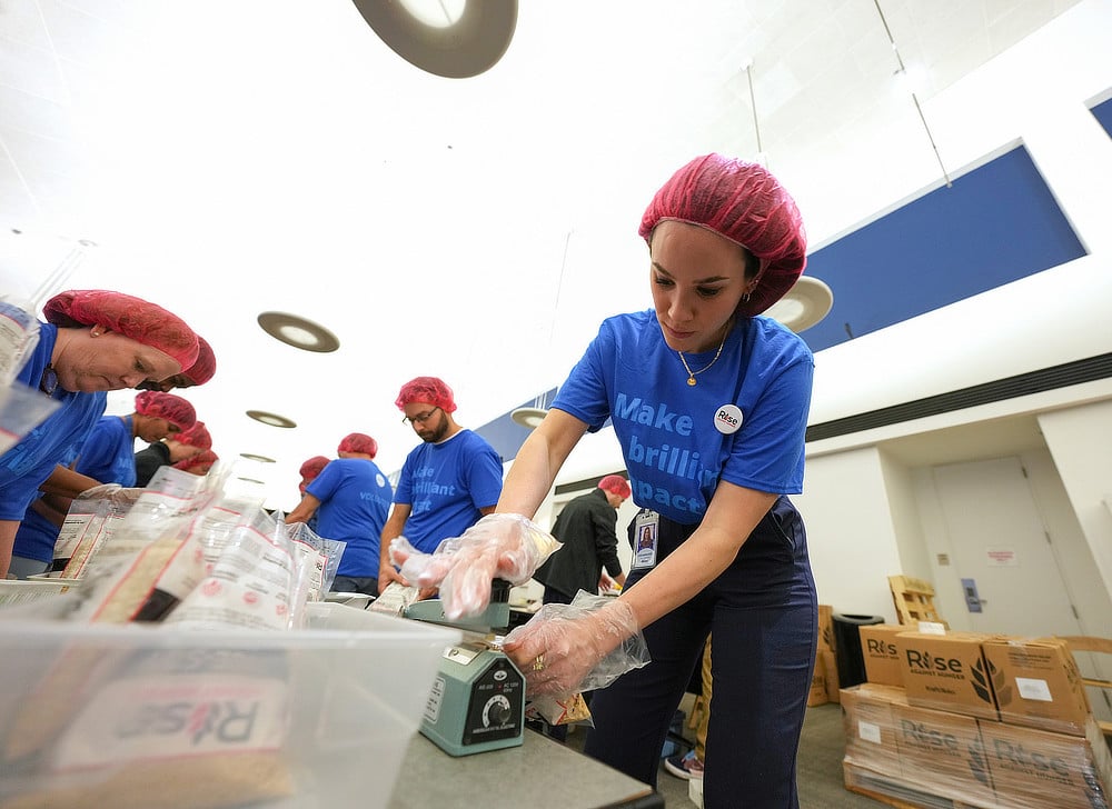Alcon employees in blue t-shirts and hair nets packing food