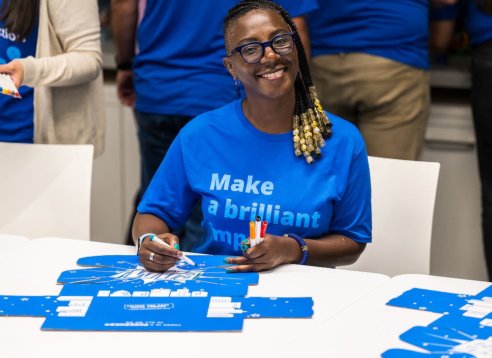 Alcon volunteer filling out packing box labels and smiling