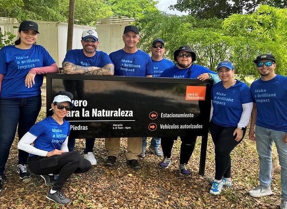 Alcon employee volunteers gathered around a park sign.