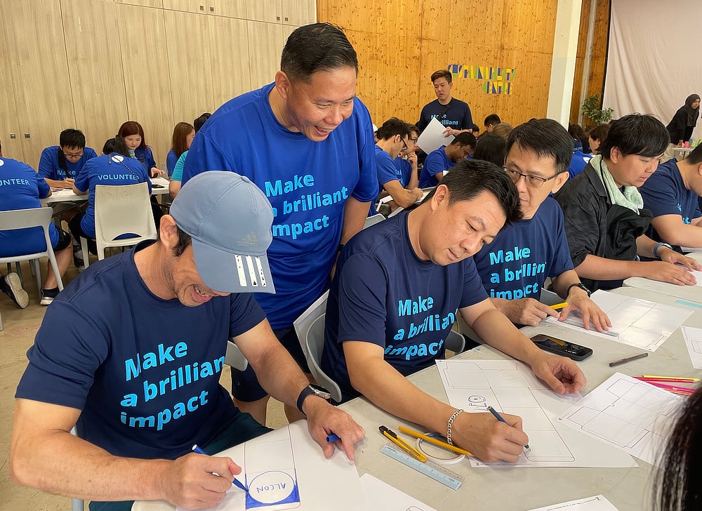 Alcon volunteers in blue t-shirts filling out forms