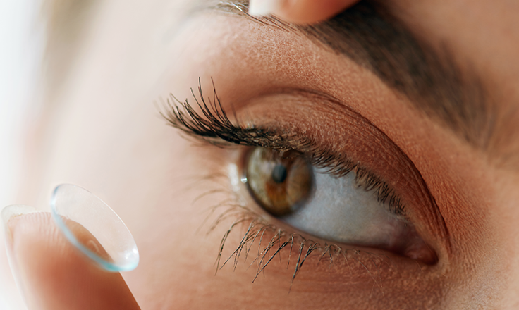 Close-up of the eye of a woman applying a contact lens